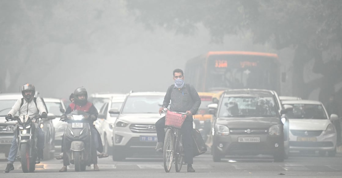 A cyclist with his face covered in cloth rides along a street on a cold smoggy morning in New Delhi on November 18, 2024. - India's capital New Delhi switched schools to online classes on November 18 until further notice because of worsening toxic smog, the latest bid to ease the sprawling megacity's health crisis. (Photo by Money SHARMA / AFP)