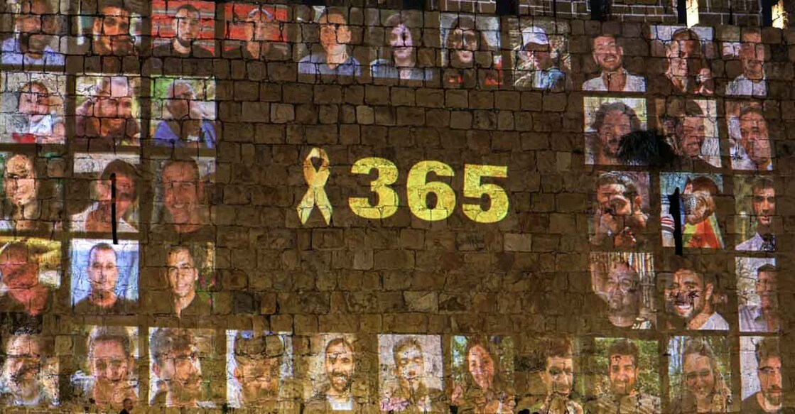 A yellow ribbon along with the number 365, signifying the number of days since the October 7, 2023 attacks carried out by Palestinian militants from the Gaza Strip, is projected along with pictures of the victims of the attacks along the old city walls of Jerusalem late on October 6, 2024 on the eve of the first anniversary of the war that began with the attacks. (Photo by Ahmad GHARABLI / AFP)