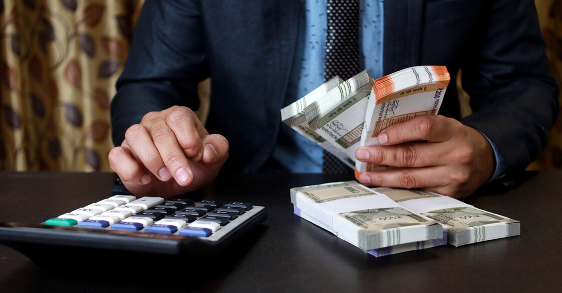 Businessman pressing calculator, calculating the conversion rate of Indian Rupee money as a return of financial investment at the table in his office indoors.