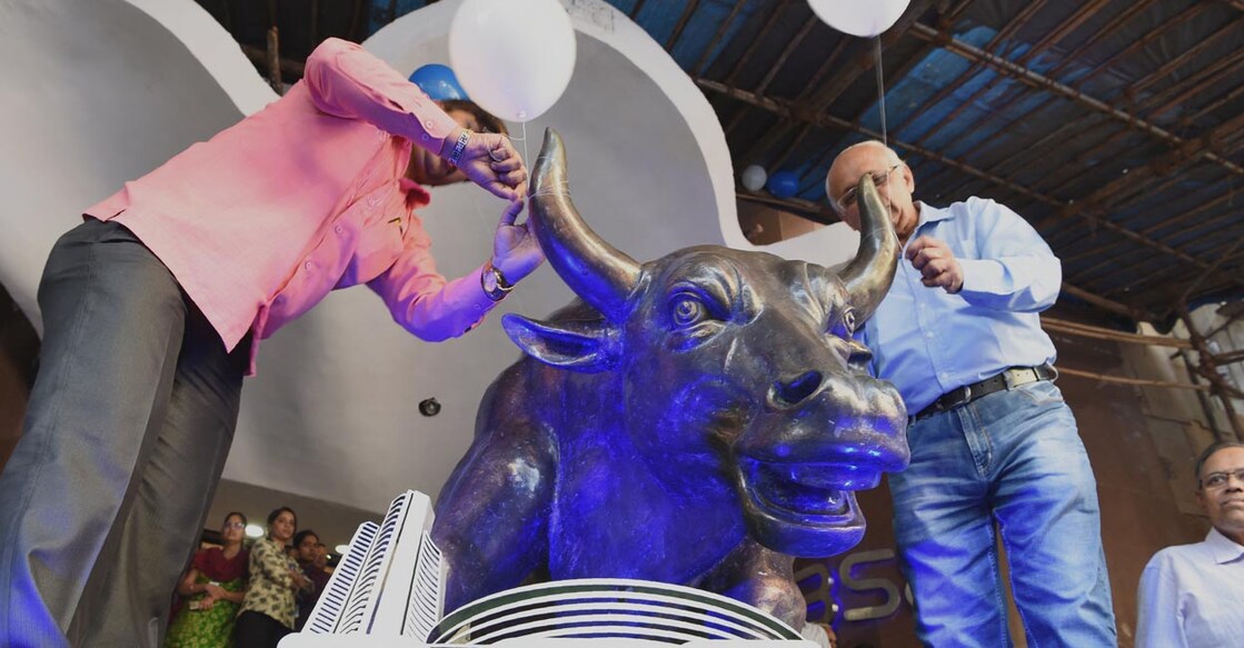Indian investors tie balloons to the bronze Bull statue outside the Bombay Stock Exchange (BSE) to celebrate the benchmark 30 share index SENSEX crossing 30,000 points in Mumbai on April 26, 2017. Indian stock markets closed at record highs on Monday 24, buoyed by increased investor confidence in the domestic economy and in line with rises across Asia. The Bombay Stock Exchange's (BSE) benchmark Sensex index rose 0.63 percent, or 190.11 points, to end the day at 30133.35. That surpassed its previous closing high of 29,926.10 a day earlier. (Photo by INDRANIL MUKHERJEE / AFP)