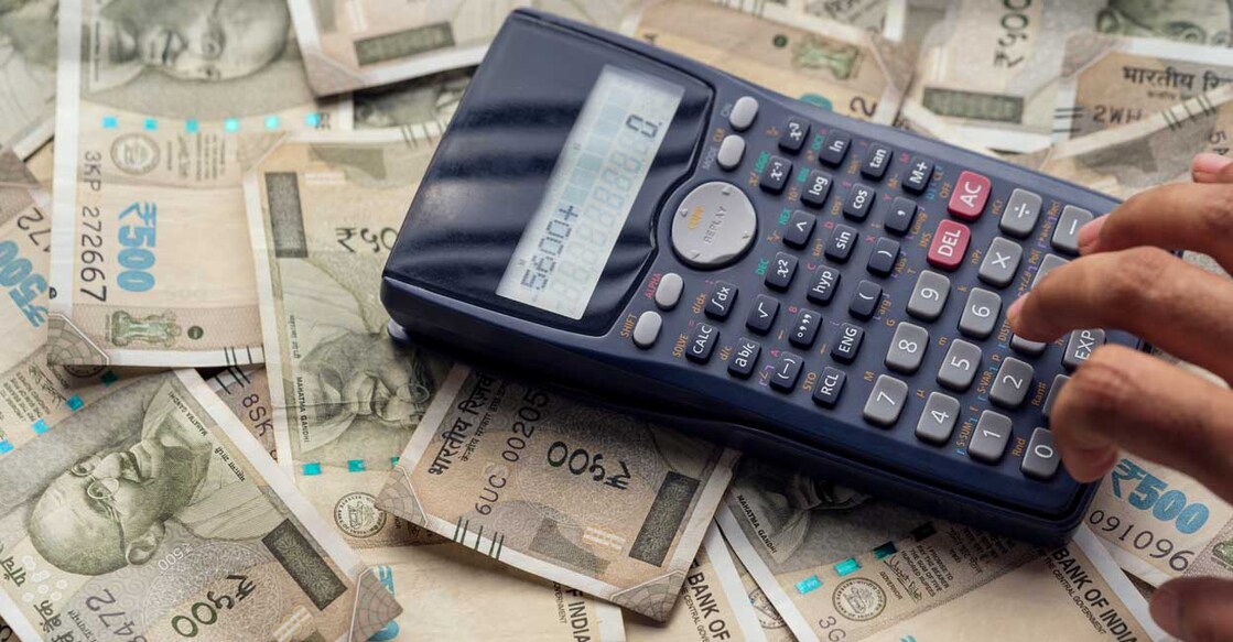 Business man pressing calculator, calculating the conversion rate of indian rupee money as a return of financial investment or monthly bills & expenses with copy space.