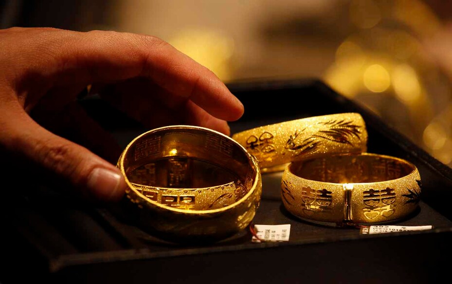 A shop attendant shows two pairs of 24K gold bracelets for Chinese weddings to a customer inside a jewellery store at Hong Kong's Tsim Sha Tsui shopping district April 24, 2013. Local and mostly mainland Chinese buyers have been crowding jewellery shops throughout the territory to buy gold since its biggest price drop in decades last week, local media reported. Gold rose more than 1 percent on Wednesday on bargain-hunting after a drop in the previous session, but pressure from a firm U.S. dollar, strong equities and daily falls in the holdings of exchange-traded funds look set to cap prices. REUTERS/Bobby Yip (CHINA - Tags: BUSINESS COMMODITIES)