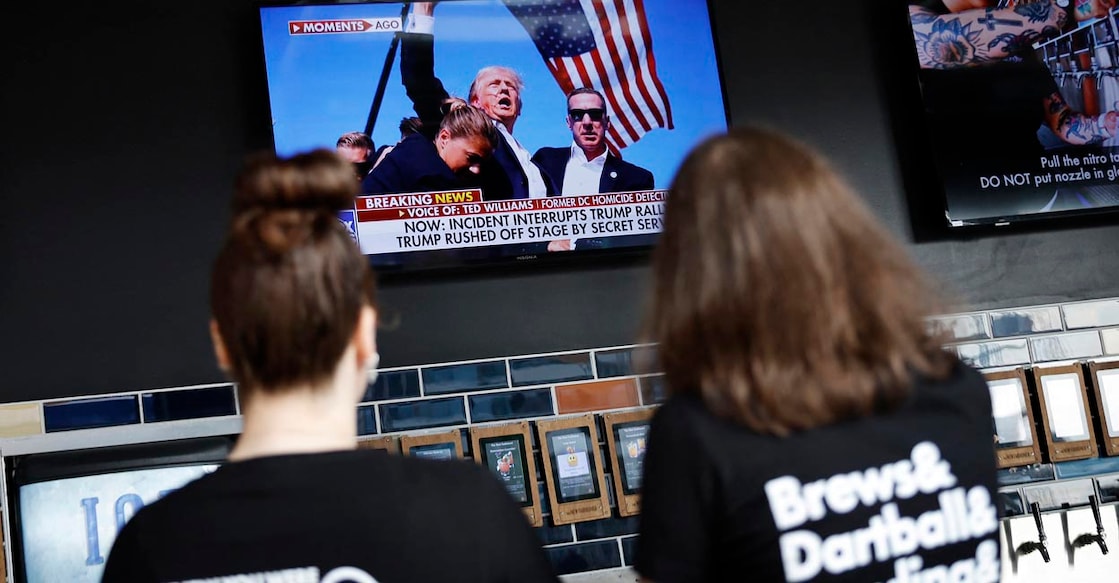 MILWAUKEE, WISCONSIN - JULY 13: People look at images of an injured former U.S. President and Republican presidential nominee Donald Trump while watch television news at The New Fashioned across the plaza from the Fiserv Forum on July 13, 2024 in Milwaukee, Wisconsin. The Republican National Convention is scheduled to take place July 15-18 at the Fiserv Forum.   Chip Somodevilla/Getty Images/AFP (Photo by CHIP SOMODEVILLA / GETTY IMAGES NORTH AMERICA / Getty Images via AFP)