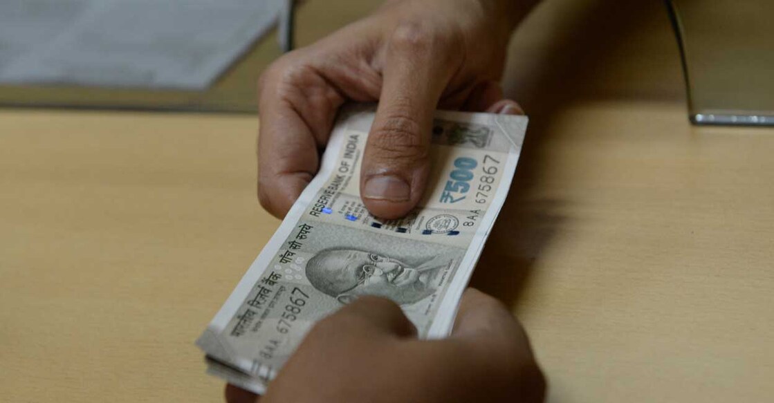 A bank staff member hands Indian 500 rupee notes to a customer on November 24, 2016, in the wake of the demonetisation of old 500 and 1000 rupee notes in Mumbai. The US dollar hit a record high against the Indian rupee November 24 as the greenback surges on expectations of a rate hike next month following Donald Trump's shock presidential election victory. The US currency bought 68.8625 rupees during early afternoon forex trading, surpassing the previous high of 68.8450 recorded in August 2013. (Photo by INDRANIL MUKHERJEE / AFP)