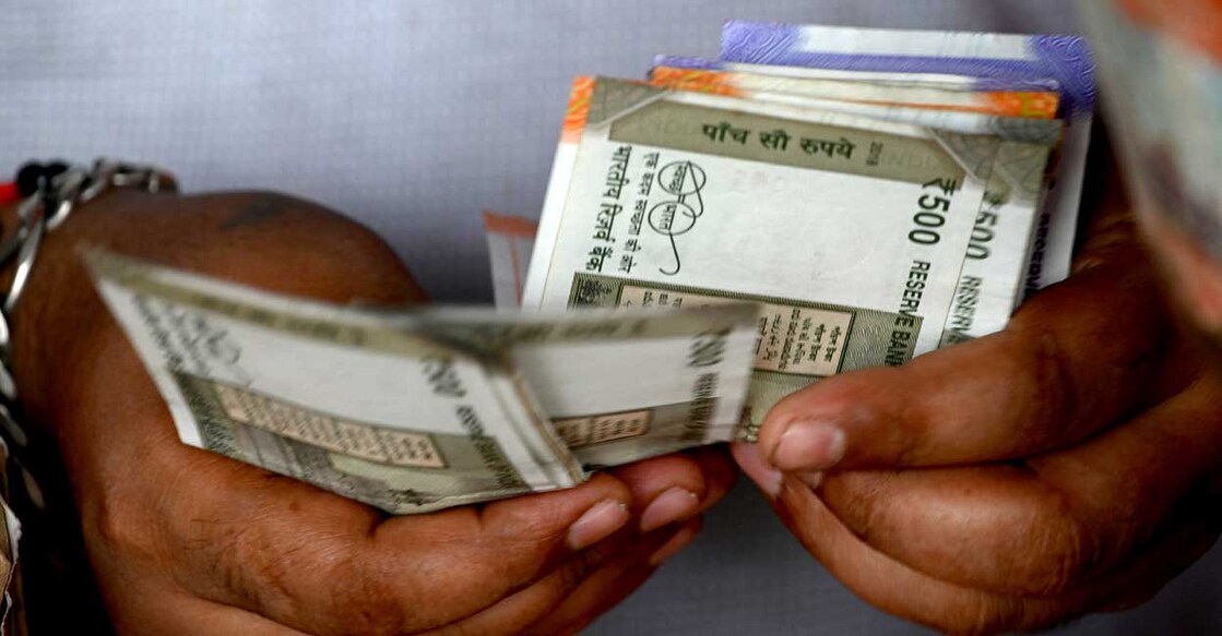 A fruit vendor counts Indian rupee notes in Mumbai on May 9, 2022. The Indian rupee plunged to a fresh all-time low against the US dollar on May 9, as aggressive US monetary policy roiled sentiment and foreign investors continued to dump domestic stocks. (Photo by INDRANIL MUKHERJEE / AFP)