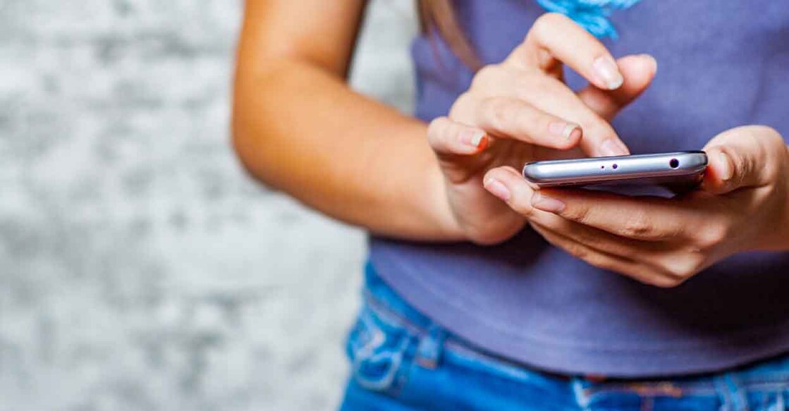 1081584578 young teenager girl hand using mobile phone or smartphone on gray wall background
