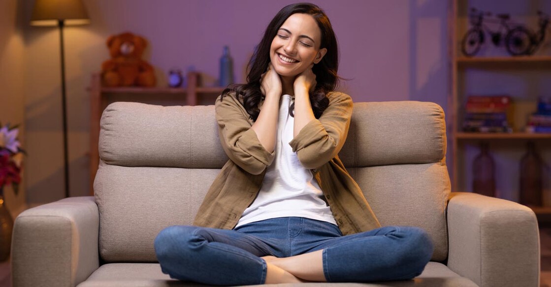 Young woman relaxing while sitting on comfortable couch in living room