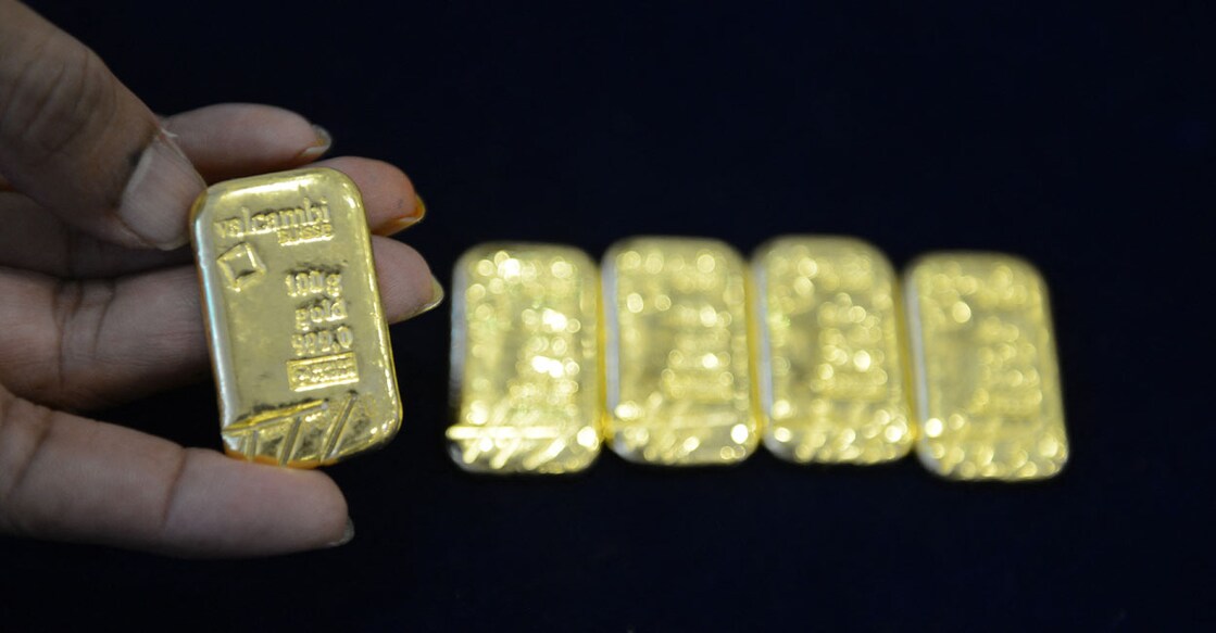 INDIA-ECONOMY-GOLD An Indian gold merchant poses with gold "biscuits" in a jewellery shop in Hyderabad on April 28, 2017, during the Hindu festival of Akshaya Tritiya. Akshaya Tritiya is considered to be an auspicious day in the Hindu calendar to buy valuables and people generally flock to buy gold on this day in the belief that it will increase their wealth. (Photo by NOAH SEELAM / AFP)