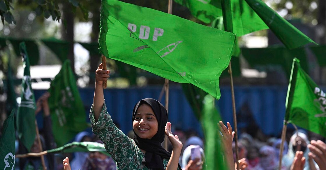 A supporter of Jammu and Kashmir People's Democratic Party (PDP) waves party's flag during the election campaign rally in Pulwama, south of Srinagar, on September 10, 2024, ahead of assembly elections in Indian-administered Jammu and Kashmir. (Photo by TAUSEEF MUSTAFA / AFP)