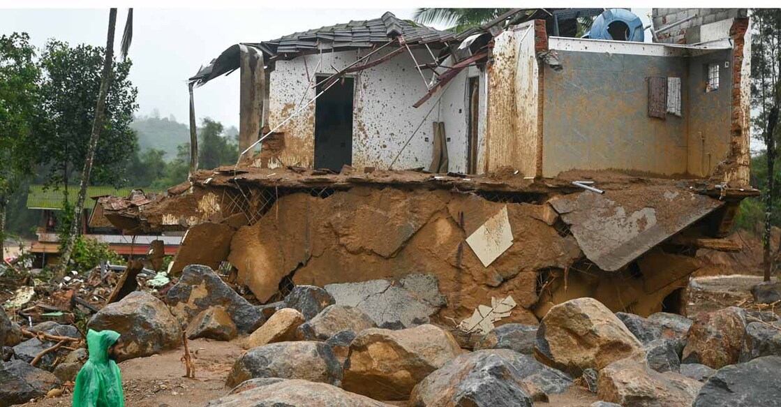 A man walks past a damaged house after the landslides in Wayanad on August 1, 2024. - Indian rescue crews scoured mud-caked tea plantations and villages on August 1 with little hope of finding more survivors from landslides that killed around 200 people. (Photo by Idrees MOHAMMED / AFP)