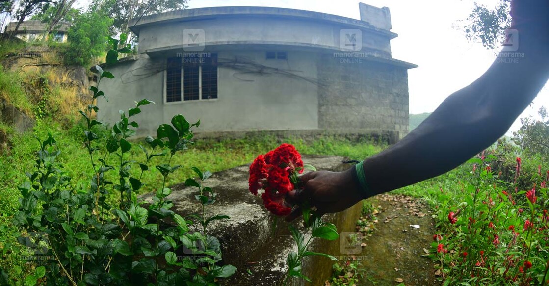 vandiperiyar-main വണ്ടിപ്പെരിയാറിൽ കൊല്ലപ്പെട്ട പെൺകുട്ടിയുടെ കുഴിമാടത്തിൽ പൂക്കൾ അർപ്പിക്കുന്ന സഹോദരൻ. പശ്ചാത്തലത്തിൽ കുടുംബത്തിന്റെ പണി തീരാത്ത വീട്. (ചിത്രം∙മനോരമ)