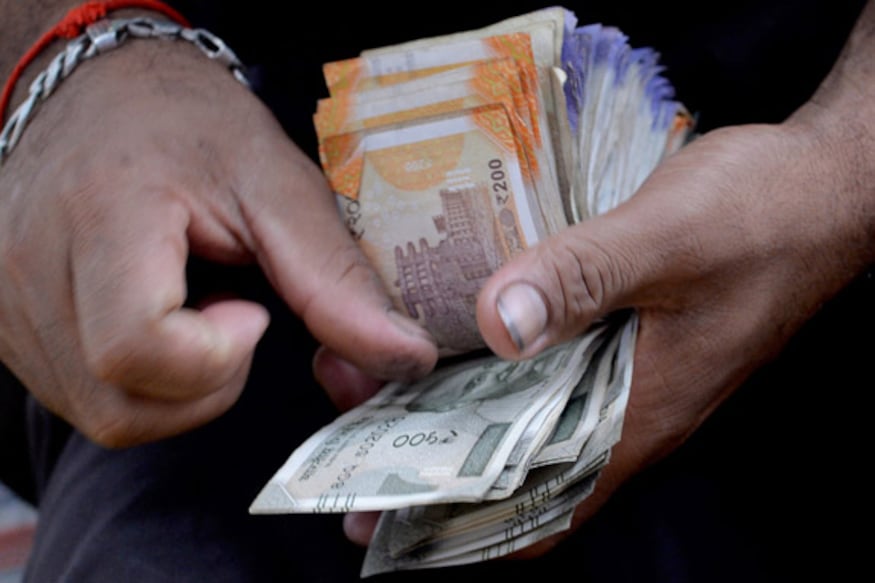 A fruit vendor counts a wad of Indian Rupee currency notes for payment at his roadside stall in Mumbai on July 19, 2022. The Indian rupee fell to more than 80 per US dollar for the first time on record on July 19, as the greenback extended its rally and foreign capital outflows intensified. (Photo by INDRANIL MUKHERJEE / AFP)