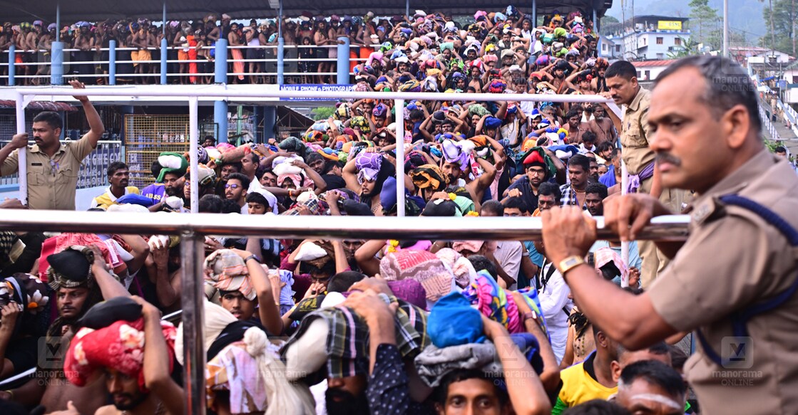 sabarimala-police-main ശബരിമല സന്നിധാനത്തെ മേൽപാലത്തിൽ തിരക്കേറിയപ്പോൾ തൂണുകൾക്ക് മുകളിൽ കയറി നിന്ന് തീർഥാടകരെ നിയന്ത്രക്കുന്ന പൊലീസ്. (ചിത്രം∙ മനോരമ)