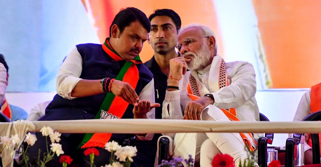 INDIA-ELECTION-VOTE India's Prime Minister Narendra Modi (R) gestures while speaking to Chief Minister of the state Devendra Fadnavis (L) as they attend a public rally in the run up to the Maharashtra state assembly elections, in Mumbai on October 18, 2019. The western Indian state of Maharashtra, currently ruled by an alliance of the Modi led Bharatiya Janata Party (BJP) and right-wing Hindu party Shiv Sena, goes to polls on October 21. (Photo by Indranil MUKHERJEE / AFP)