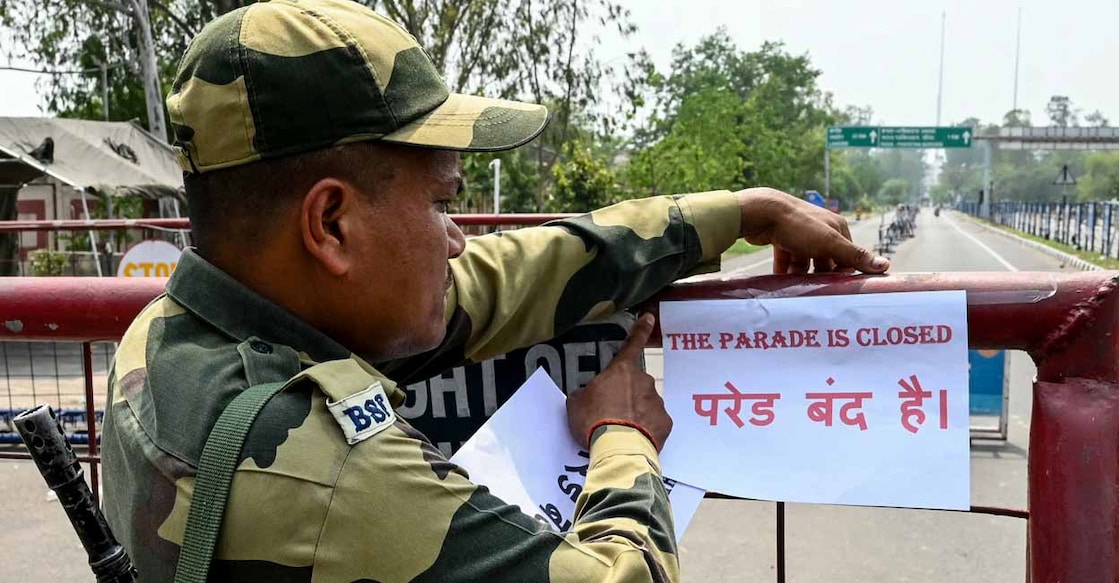 INDIA-PAKISTAN-KASHMIR-UNREST An Indian Border Security Force (BSF) personnel places a poster that reads, "The Parade is closed" atop a barricade as the Beating Retreat ceremony is closed for visitors at the India and Pakistan Wagah border post, near Amritsar, on May 7, 2025, as border tensions rise following Indian strikes in Pakistan. India and Pakistan exchanged heavy artillery fire along their contested frontier on May 7 after New Delhi launched deadly missile strikes on its arch-rival, in the worst violence between the nuclear-armed neighbours in two decades. (Photo by Narinder NANU / AFP)