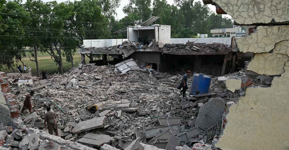 PAKISTAN-INDIA-KASHMIR-UNREST Locals stand on the debris of destroyed structures at the Government Health and Educational complex in Muridke about 30 kilometres from Lahore, on May 7, 2025, after Indian strikes. The death toll from Indian strikes on Pakistan has increased to eight, the country's military spokesman said on May 7, as India fired missiles at Pakistani territory and Islamabad vowed to "settle the score". (Photo by FAROOQ NAEEM / AFP)