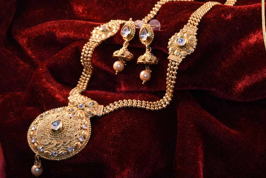 1129340287 Designer beautiful golden neck set closeup macro image on red background.