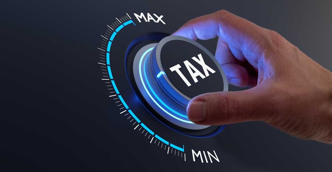 Tax reduction and deduction for businesses and individuals. Concept with hand turning knob to low taxation rate. Return form, exemptions, incentives.