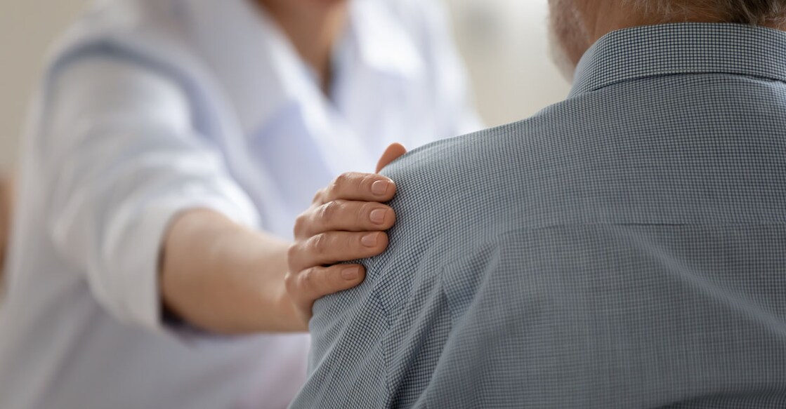 Close up caring doctor touching mature patient shoulder, expressing empathy and support, young woman therapist physician comforting senior aged man at meeting, medical healthcare and help