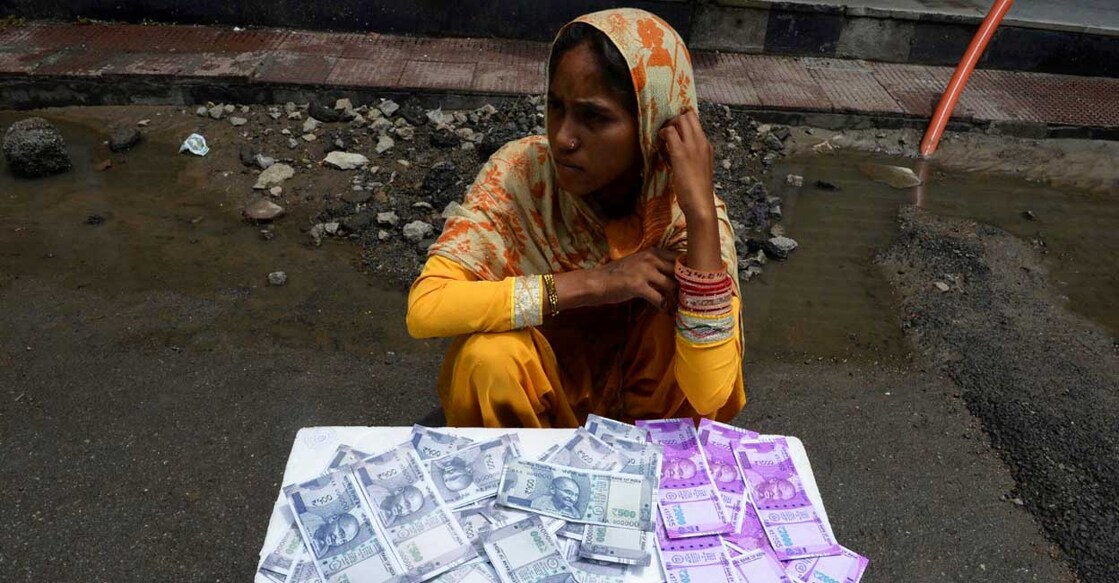 INDIA-ECONOMY-CURRENCY 500, 2000 രൂപ നോട്ടുകളുടെ ഡിസൈനിൽ നിർമിച്ചിരിക്കുന്ന പഴ്സുകൾ വിൽക്കുന്ന യുവതി. ഹൈദരാബാദിൽനിന്നുള്ള കാഴ്ച (File Photo by Noah SEELAM / AFP)