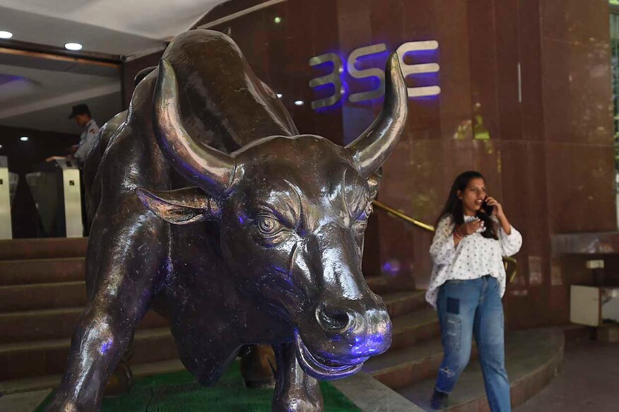 A woman talks on her phone next to a bronze sculpture of a charging bull during intraday trade inside the premises of the Bombay Stock Exchange (BSE) building in Mumbai on February 28, 2020. (Photo by Punit PARANJPE / AFP)