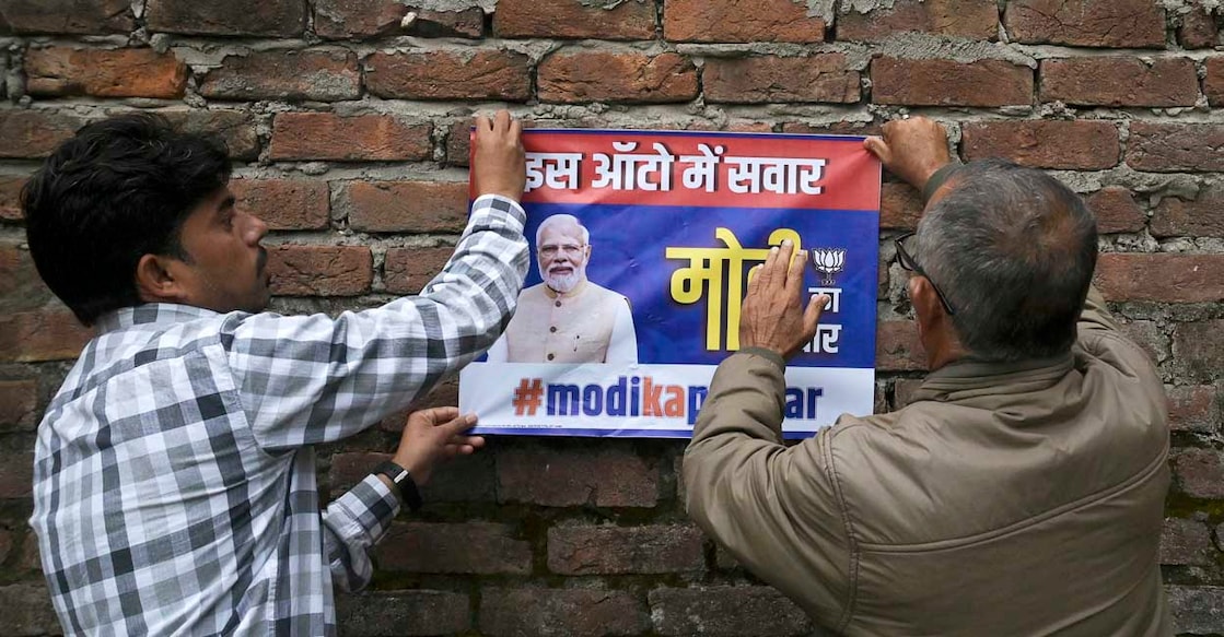 Bhartiya Janta Party (BJP) activists paste a poster with the image of BJP leader and Indian Prime Minister Narendra Modi on a wall near a polling station during the first phase of voting of India's general elections in Jammu, some 230 Kms from Srinagar on April 19, 2024. (Photo by TAUSEEF MUSTAFA / AFP)