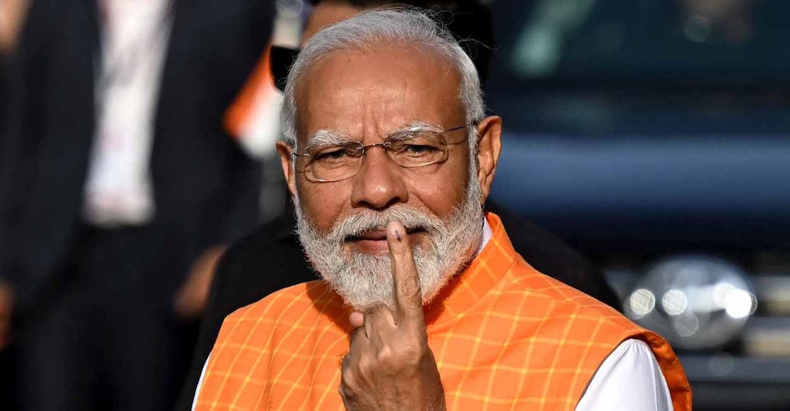 India's Prime Minister Narendra Modi (C), leader of the ruling Bharatiya Janata Party (BJP) displays his inked marked finger after casting his ballot at a polling booth at Ranip, Ahmedabad on May 7, 2024. (Photo by Sajjad HUSSAIN / AFP)