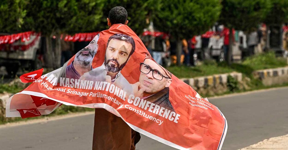 A supporter of the Jammu and Kashmir National Conference (NC) party carries a banner with pictures of party leaders during an election campaign rally addressed by candidate Aga Syed Ruhullah Mehdi in Srinagar on May 11, 2024, ahead of the fourth phase of voting of India's general election. (Photo by TAUSEEF MUSTAFA / AFP)