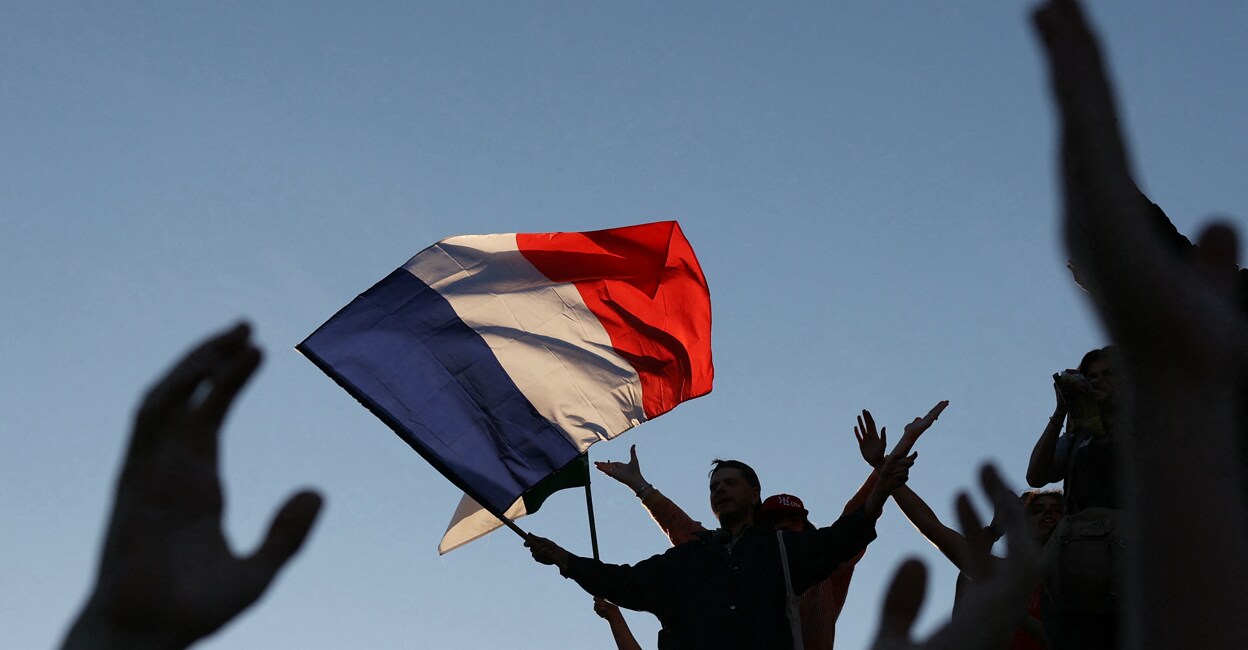 French national flag An attendee flys a French national flag during a gathering for the election night following the the second round results of France's legislative election at Republique Square in Paris. (Photo by Alain JOCARD / AFP)